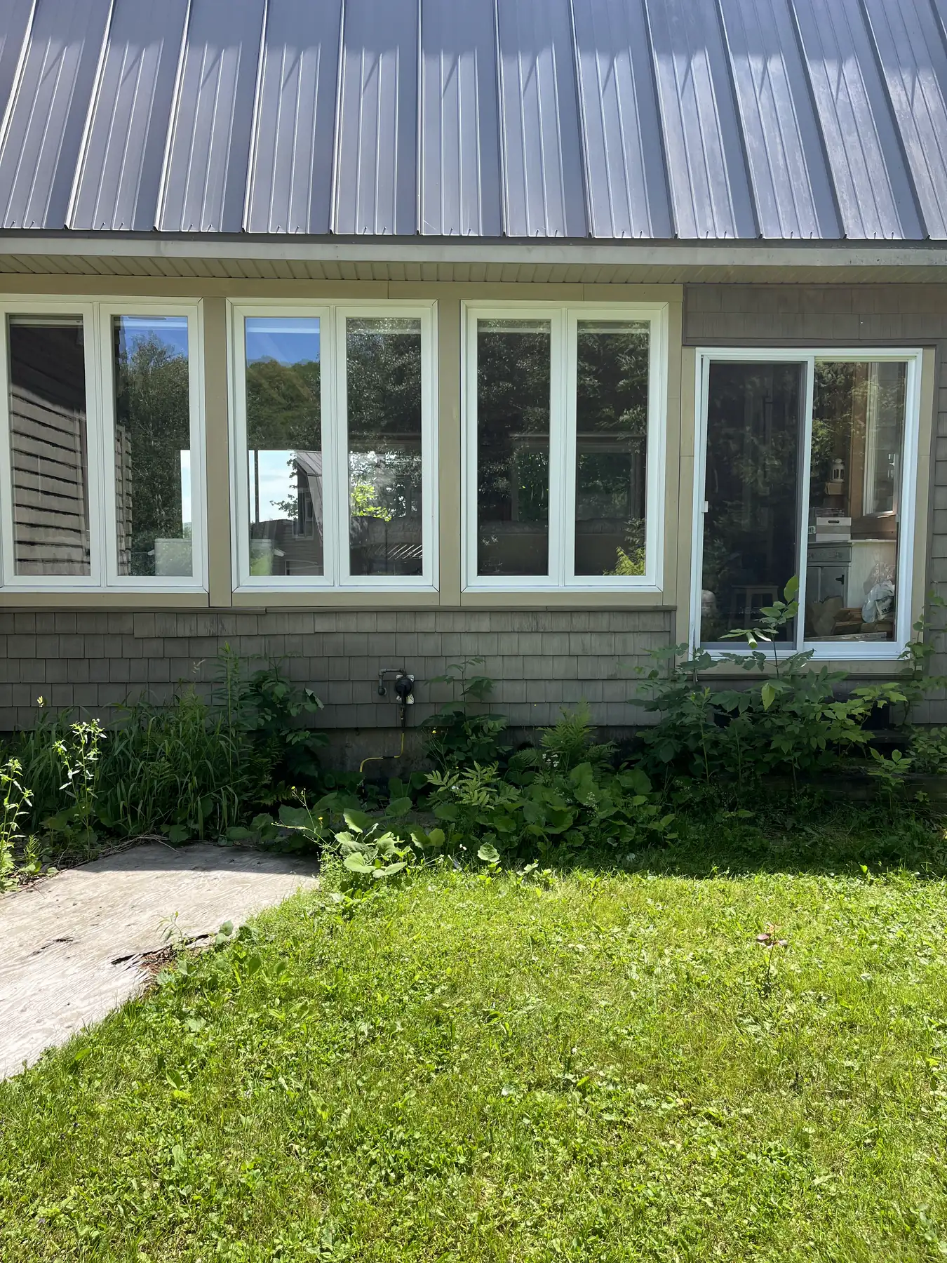 Rangée de fenêtres à cadres blancs sur une maison de campagne à bardeaux